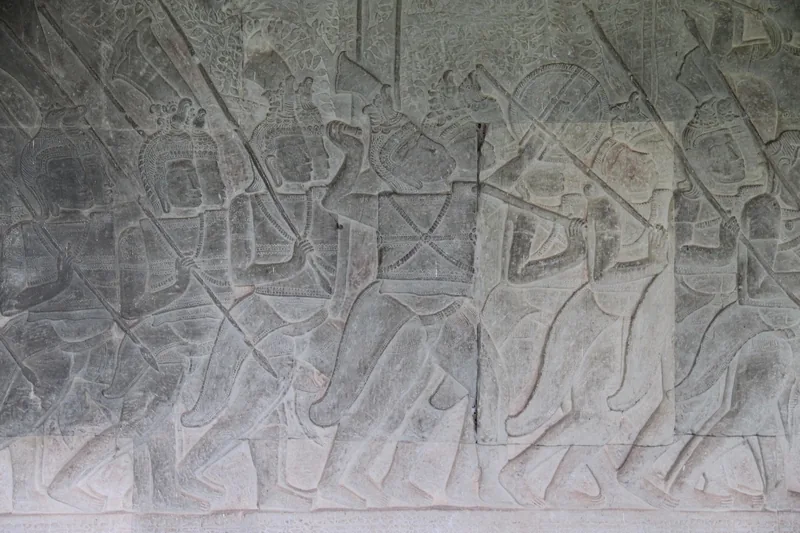 Ancient stone bas-relief of armed soldiers marching in procession carved into a temple wall at Angkor Wat, Siem Reap.