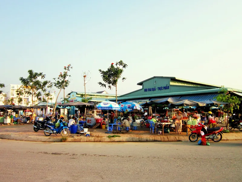 A local market street with vendor stalls, umbrellas, and parked motorbikes under a wide roof in Can Tho.