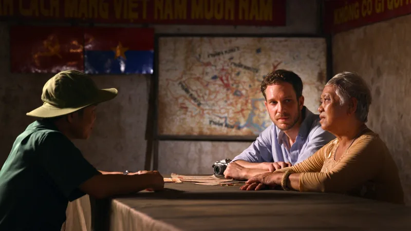 Visitors sit at a table with a local guide beneath a war map and revolutionary banners at Cu Chi tunnels site.