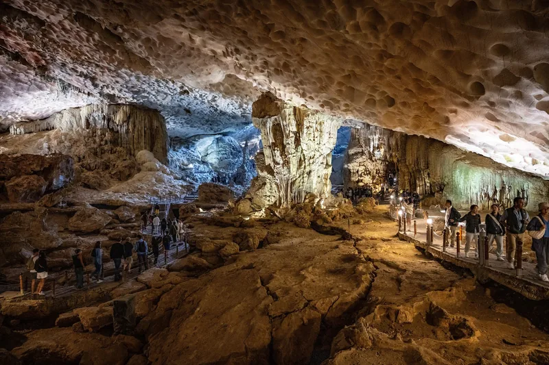 Tourists walk along a lit pathway through the vast limestone chamber of Sung Sot Cave in Ha Long Bay.