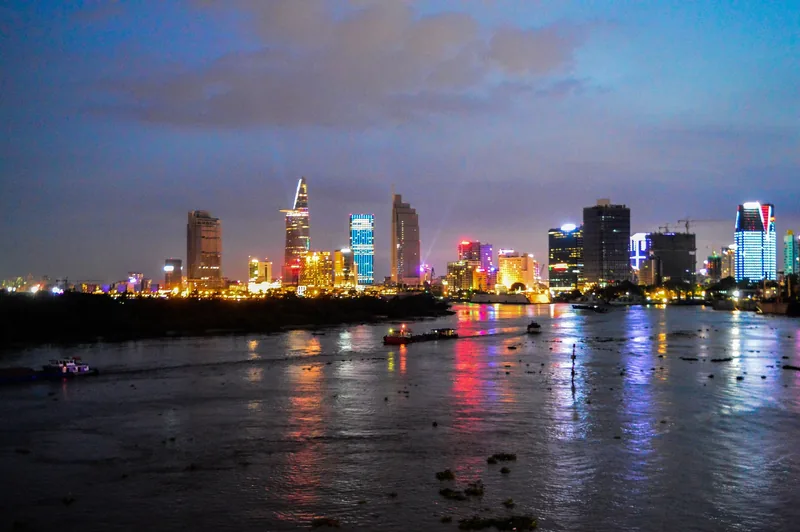 Ho Chi Minh City's illuminated skyline glows above the Saigon River at dusk.
