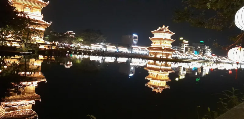 Illuminated pagoda towers reflect on a calm river at night in Ninh Binh.