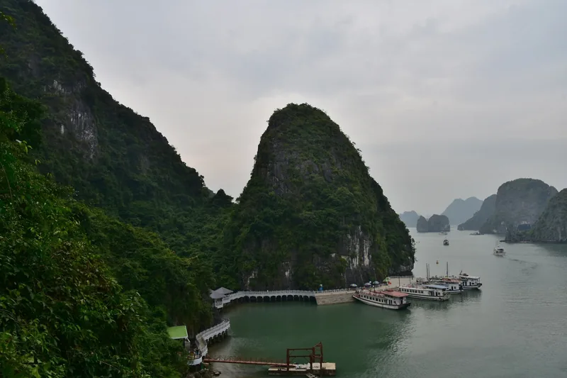 Limestone karsts rise over a jetty and moored boats in Ha Long Bay, Vietnam.